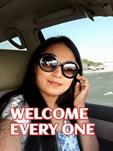 a woman wearing sunglasses is sitting in a car with the words welcome every one