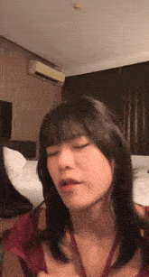 a woman is making a funny face in a room with a air conditioner on the wall .