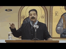 a man is standing at a podium giving a speech in front of a microphone and a glass of water .