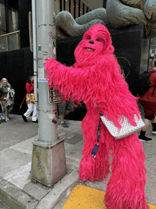 a person dressed in a pink chewbacca costume holds onto a pole