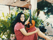 a woman in a pink dress holds a guitar with the letter m on it