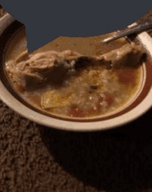 a bowl of soup with a spoon in it is sitting on the floor .