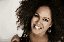 a woman with curly hair and earrings is smiling .