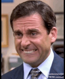 a man in a suit and tie is smiling and making a face .