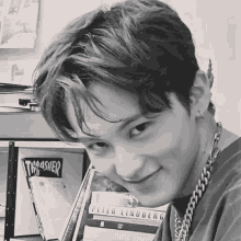 a black and white photo of a young man standing in front of a stack of books including thrasher and peter lindberg