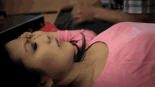 a woman in a pink shirt is laying on her stomach