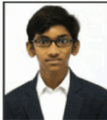 a young boy wearing glasses and a suit is posing for a picture .