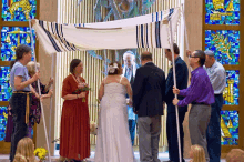 a bride and groom are getting married under a canopy with a stained glass window behind them