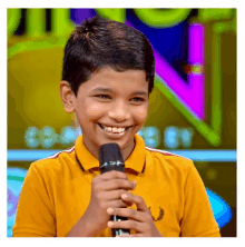 a young boy wearing a yellow shirt is smiling while holding a microphone