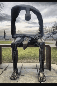 a large statue of a person sitting on a bench