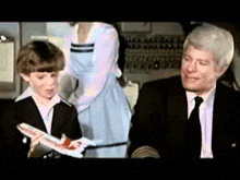 a man and a boy are sitting on a plane . the boy is holding a model airplane in his hand .