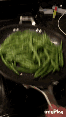 green beans are being cooked in a frying pan on a stove with imgplay written in the lower right corner