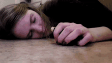 a woman laying on the floor with a gold ring on her finger