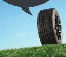 a car tire is on a grassy hill with a speech bubble above it