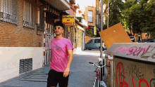 a man in a pink shirt is walking down a street in front of a yellow sign that says la boutique del arreglo