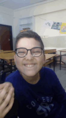 a young boy wearing glasses and a college shirt smiles for the camera