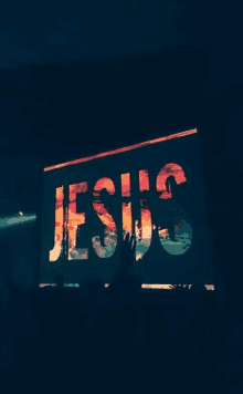 the word jesus is displayed on a screen in a dark room