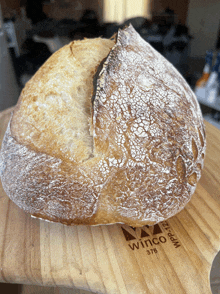 a loaf of bread is sitting on a wooden cutting board that says winco 378