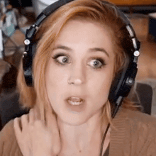 a close up of a woman wearing headphones making a funny face .
