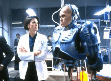 a woman in a white coat is standing next to a robot .