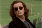 a man with red hair is wearing sunglasses and a black jacket .