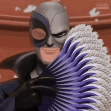 a man in a superhero costume is holding a purple fan in front of his face .