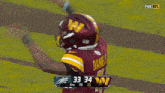 a football player wearing a helmet with the score 33-34