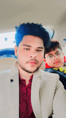 a man in a suit is sitting next to a young boy in a car