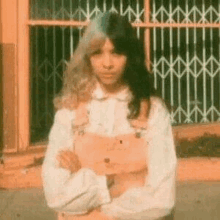 a young girl is standing in front of a window with her arms crossed .