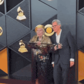 a man in a suit stands next to a woman on a red carpet