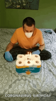 a man wearing a mask is sitting on a bed with a birthday cake made out of toilet paper .