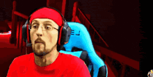 a man wearing headphones and a red headband is sitting in a blue chair with the letter e on it