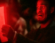 a man with a surprised look on his face is looking at a red light .