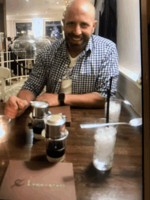 a man in a plaid shirt sits at a table in front of a menu that says lemongrass