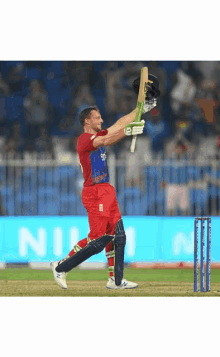 a cricket player holds up his bat in the air while wearing a shirt that says ' england ' on it