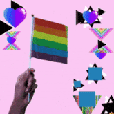 a hand is holding a small rainbow flag