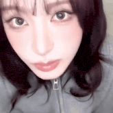 a close up of a woman 's face with a zipper on her jacket and red lips .