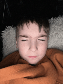 a young boy with his eyes closed laying on a blanket