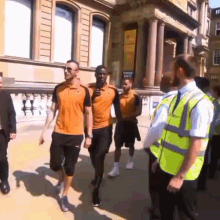 a group of men are walking down a street in front of a building with a sign on it that says ' public exit '