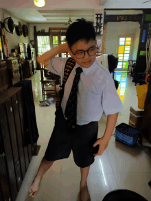 a boy with glasses and a tie is standing in a room