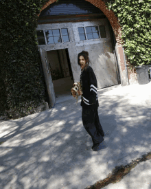 a woman is walking a dog in front of a garage