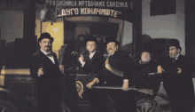 a group of men standing in front of a sign that says " dugo konacmite "