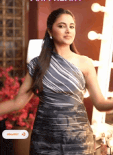 a woman in a striped one shoulder dress is standing in front of a mirror with ddev007 written on the bottom right