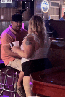 a man and a woman sit at a bar with hdr displayed on the screen