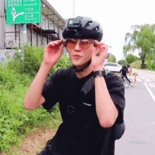 a man wearing a helmet and sunglasses is standing in front of a sign that says ' korean park '