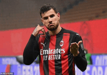 a soccer player wearing a red and black jersey with emirates fly better written on it