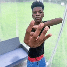 a young man is giving the middle finger to the camera while standing in front of a field .