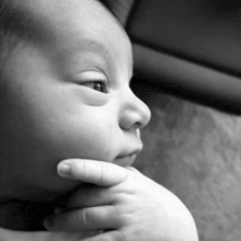 a close up of a baby 's face with a hand on its chin