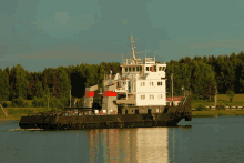 a large ship is floating on the water with trees in the background