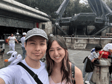 a man and a woman are posing for a picture in front of a building that says ' disneyland ' on it